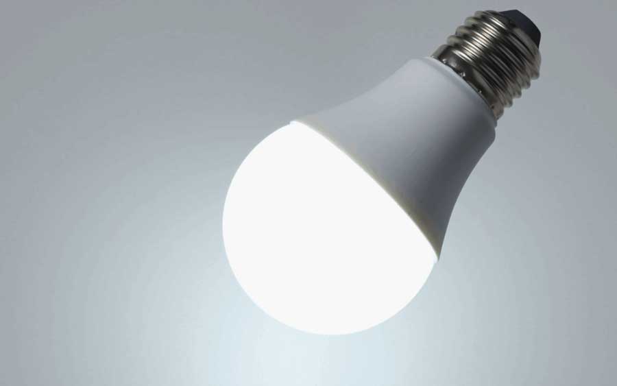 A glowing white LED light bulb with a metallic base on a plain background.