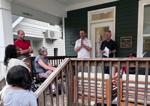 A group of people on a porch engaged in Aging in Placers discussion, with Commissioner Ted Terry speaking and others listening attentively.